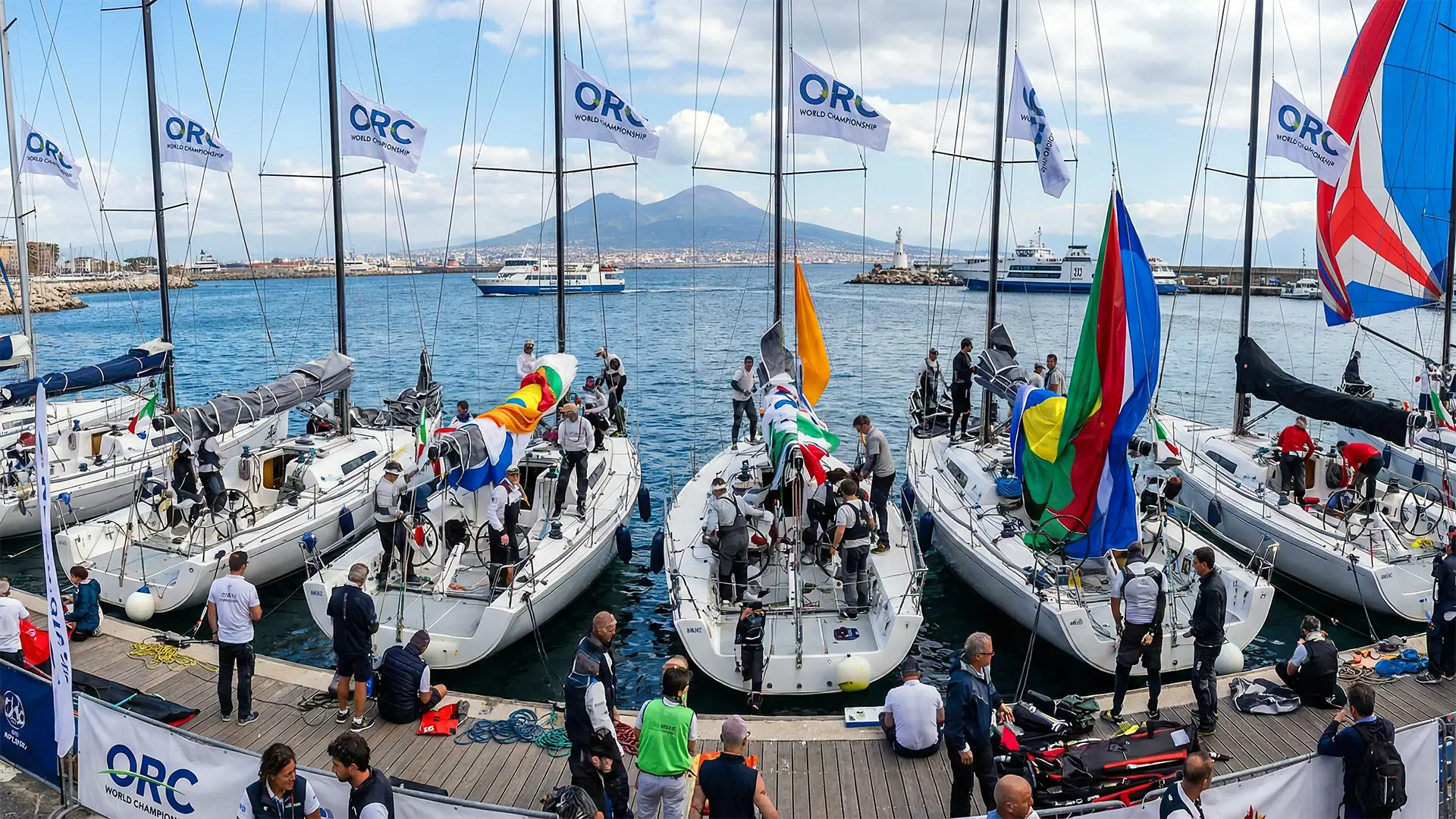 Sailboats docked at Sorrento Marina with ORC World Championship flags, crews prepping on deck, and Mount Vesuvius in the background.